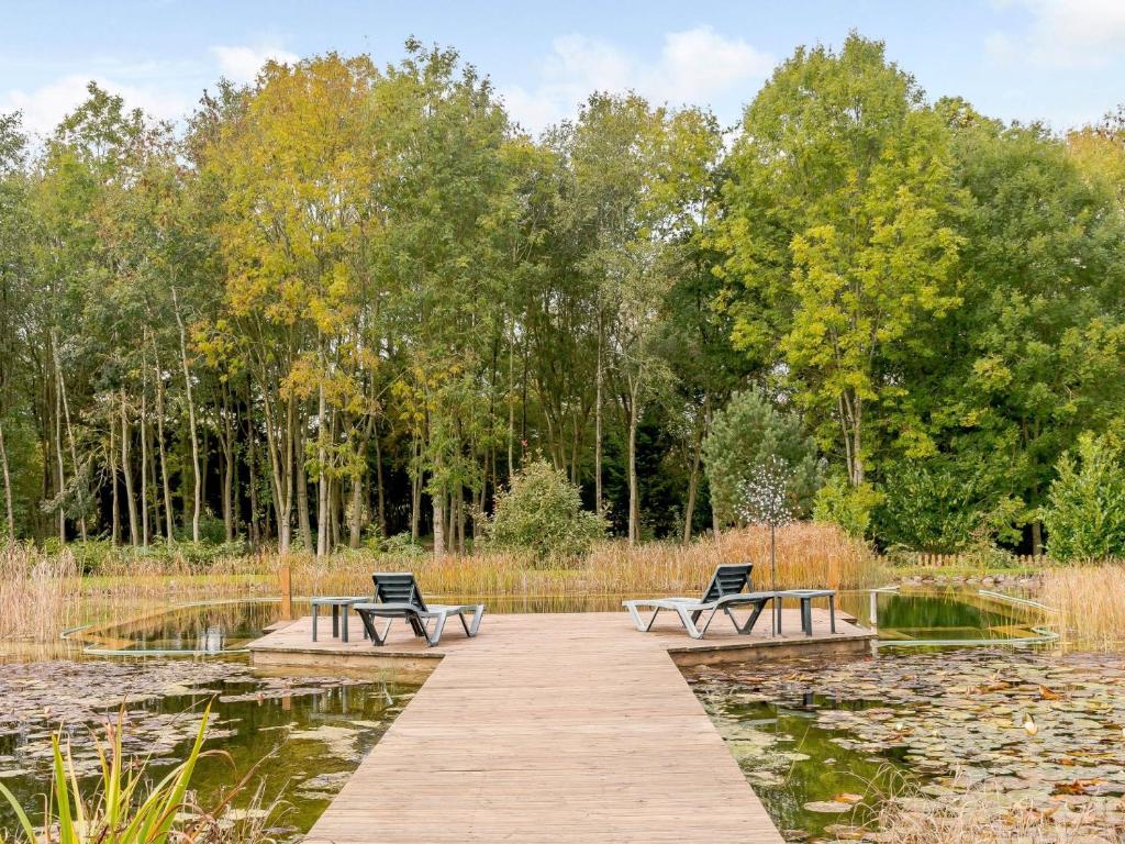 two benches sitting on a wooden walkway over a pond at 3 Bed in Ledbury 77379 