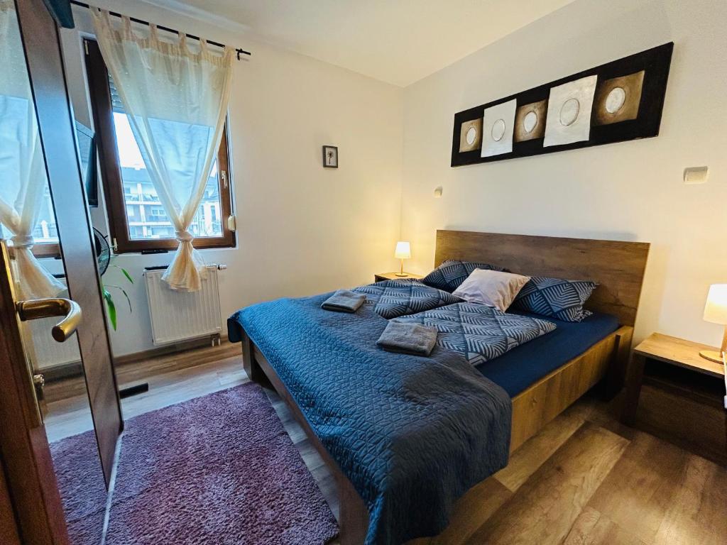 a bedroom with a bed with blue sheets and a window at Marcello Wellness Apartment in Siófok