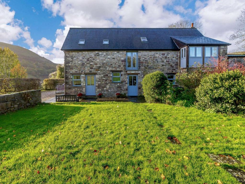een stenen huis met een groen gazon ervoor bij 4 Bed in Abergavenny 90003 in Gilwern