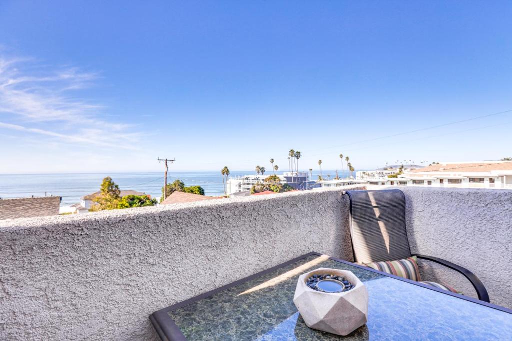 a table and chair on a wall with a view of the ocean at Pismo Beach Condo with Balcony Near Wineries! in Pismo Beach