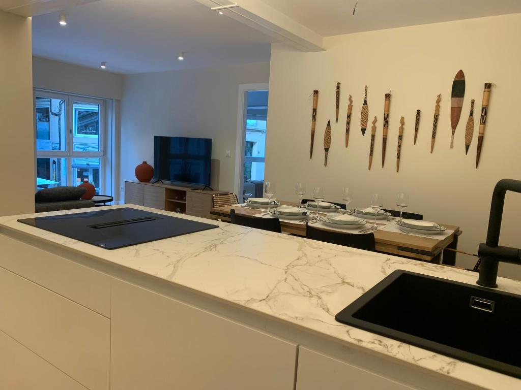 a kitchen with a counter and a living room at LAS TERRAZAS I Lujo frente a la plaza de Santa Eufemia in Ourense