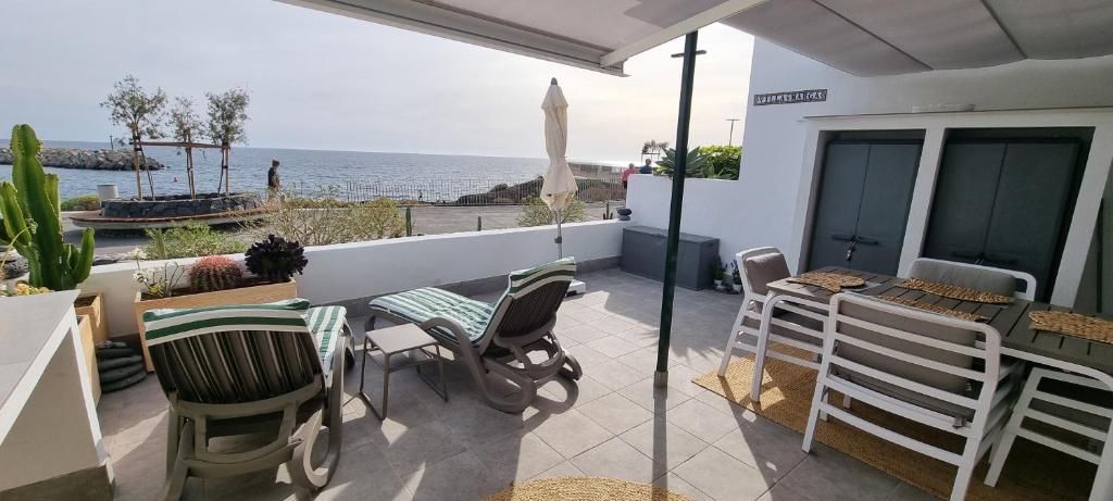 a patio with chairs and a table and a view of the ocean at Oceanfront Villa - Tenerife South in San Miguel de Abona