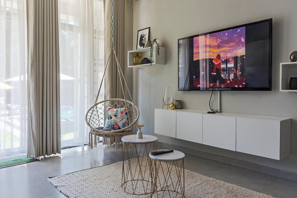 ein Wohnzimmer mit einem Flachbild-TV auf einem weißen Schrank in der Unterkunft 31 on Forest Road (FatsoDelux) in Johannesburg