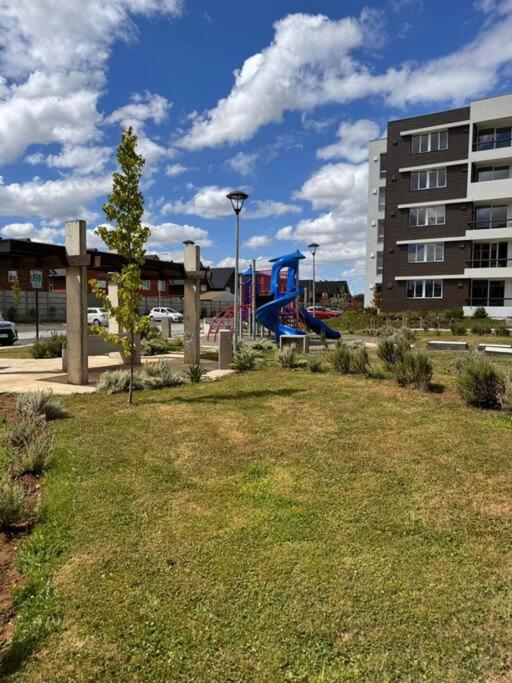 un parc avec une aire de jeux en face d'un bâtiment dans l'établissement Moderno Departamento, à Osorno