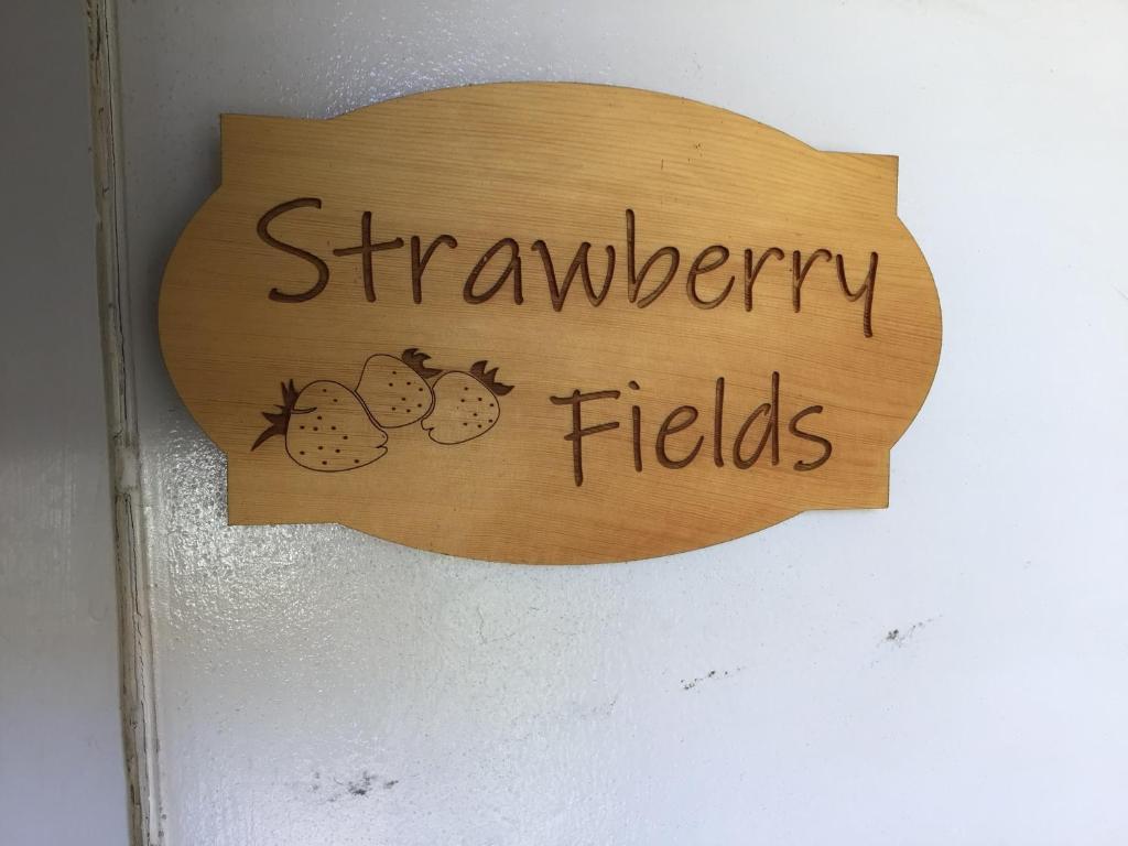 un cartel en una pared que lee campos de fresa en Strawberry fields, en Devonport