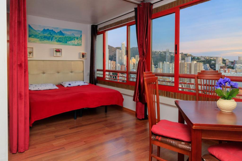sypialnia z czerwonym łóżkiem, stołem i oknem w obiekcie SUNSHINE Apartament w mieście Benidorm