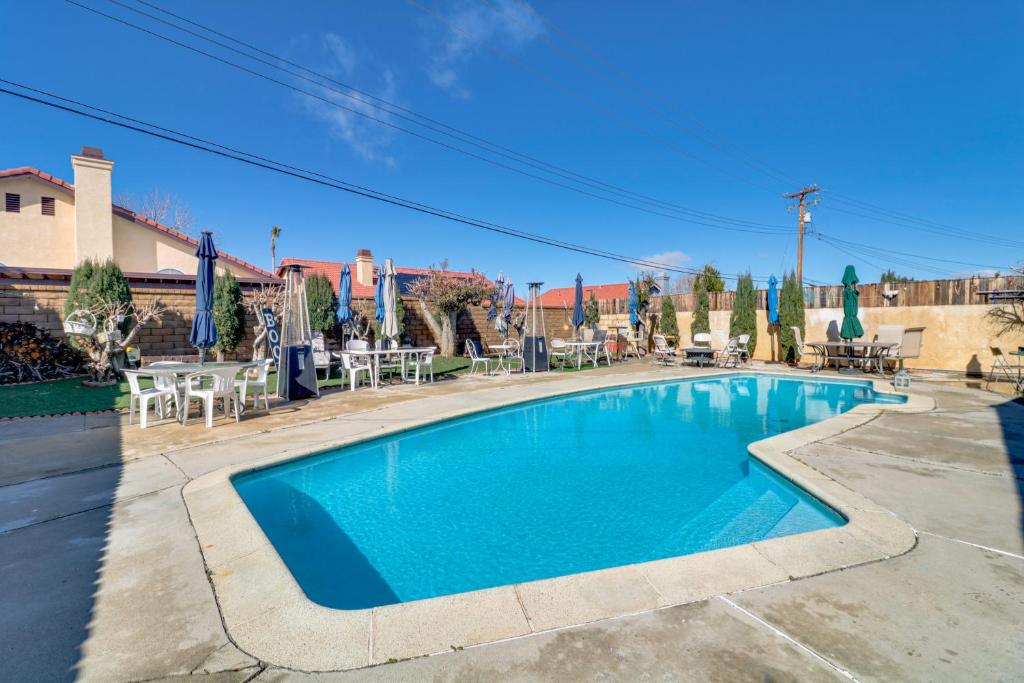 una piscina azul con mesas y sombrillas en Palmdale Family Home with Private Pool and Backyard en Palmdale