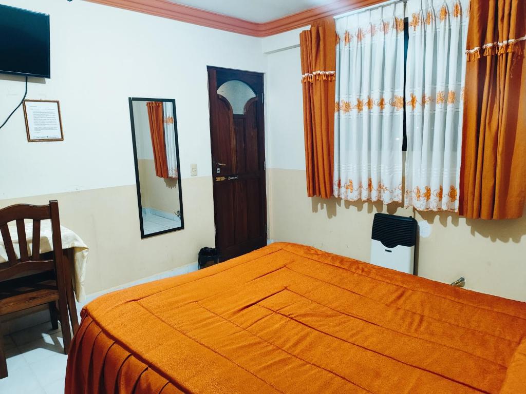 een slaapkamer met een bed met een oranje deken erop bij HOTEL IDEAL in Villazón