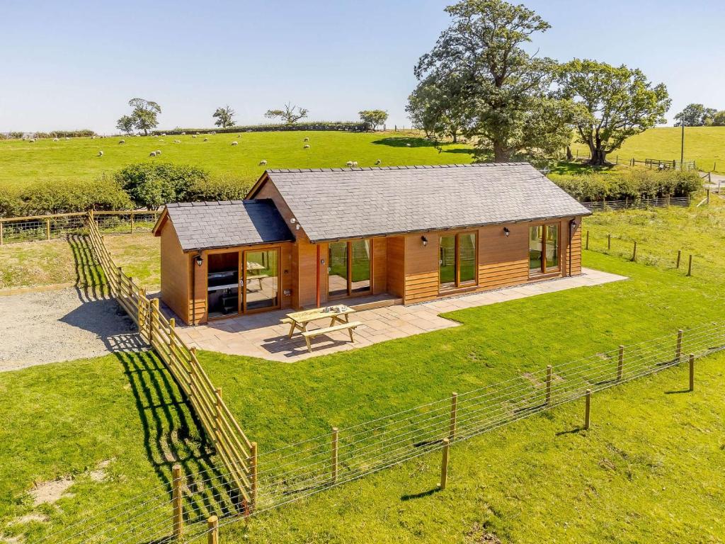 a wooden cabin in a field with a fence at 2 Bed in Llandrindod Wells 89064 in Nantmel