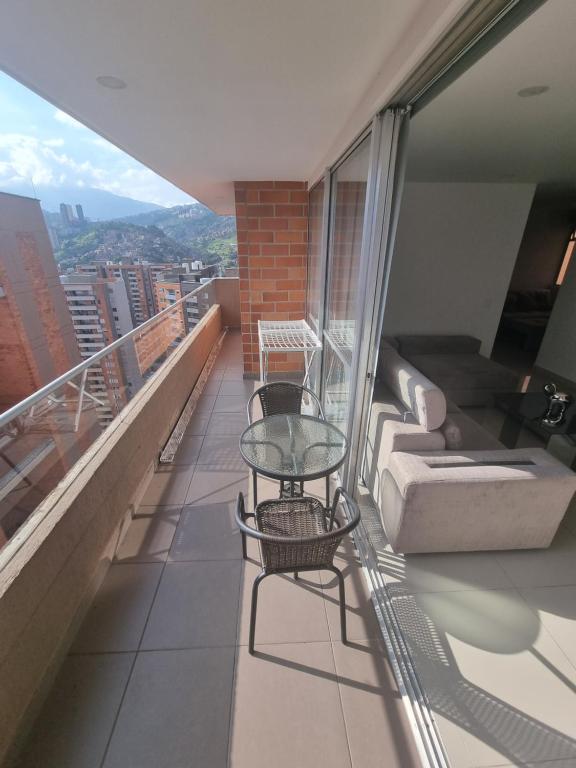 een balkon met een glazen tafel en een bank bij Cómodo apartamento in Medellín