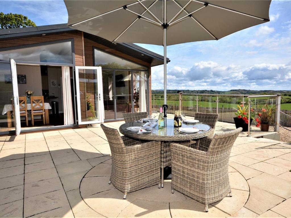 a patio with a table and chairs with an umbrella at 2 Bed in Lochwinnoch 55854 in Kilmacolm