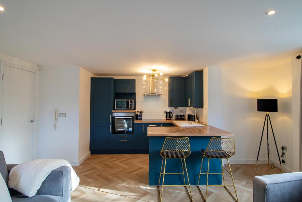 a kitchen with blue cabinets and two bar stools at Newcastle City Apartments - FREE Parking Baltic Quay in Gateshead