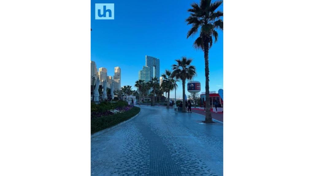 an empty street with palm trees and a city at Urban Heaven, Premium Hostel - JBR - Walk To Beach, Metro Station in Dubai