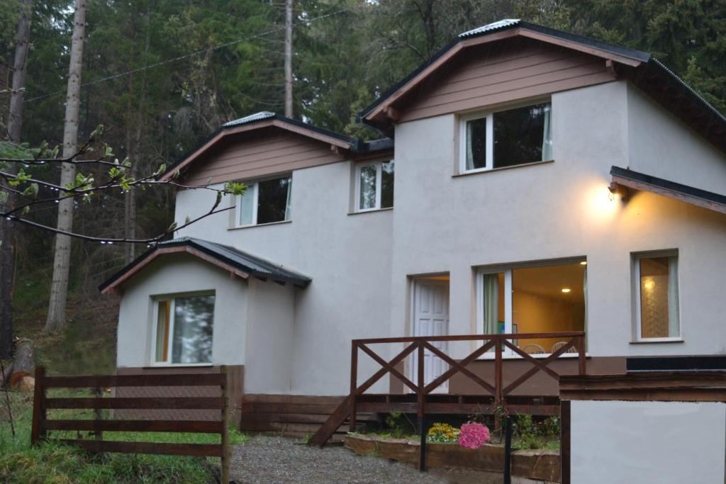 une maison blanche avec une clôture devant elle dans l'établissement Casa Llao alojamiento de montaña, à San Carlos de Bariloche