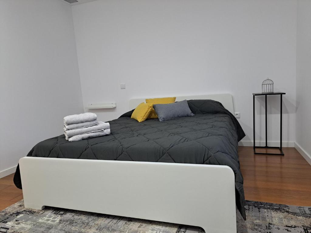 a bedroom with a black bed with yellow and blue pillows at Casa de Baixo in Paredes de Coura
