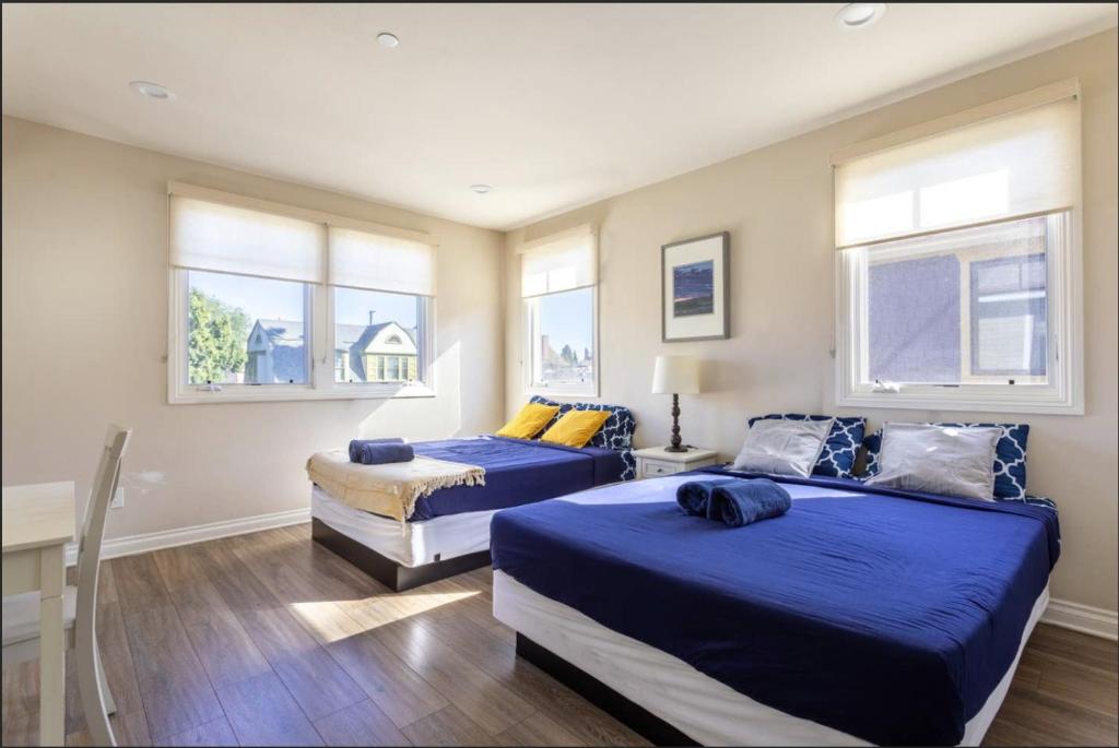 two beds in a room with two windows at Shared Living Los Angeles (South K-Town) in Los Angeles