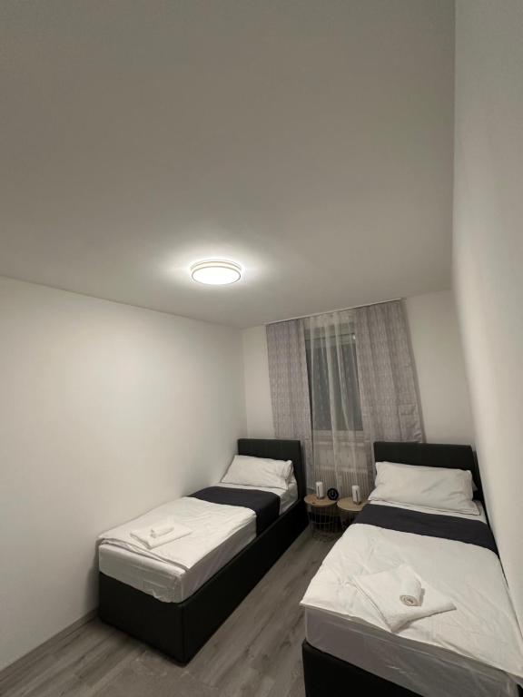 Duas camas num pequeno quarto com paredes brancas em Familien Apartment em Niederaigen