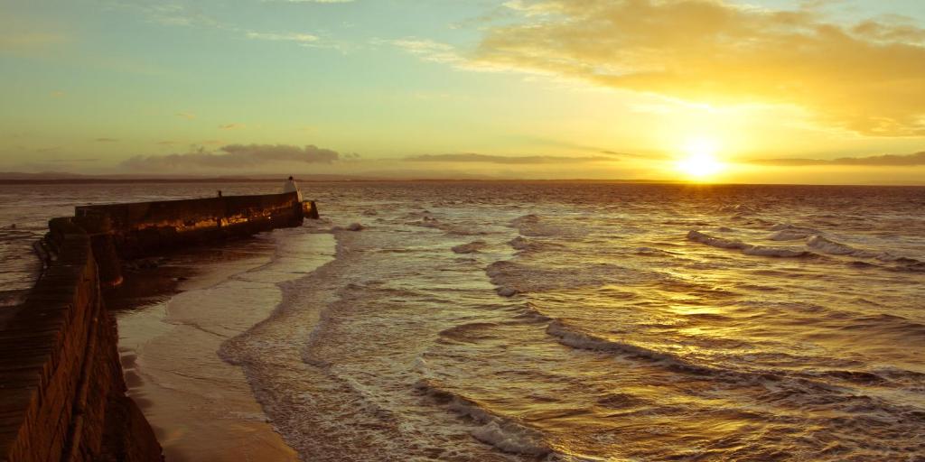 a sunset over the ocean with a pier at Firth View, Burghead in Burghead