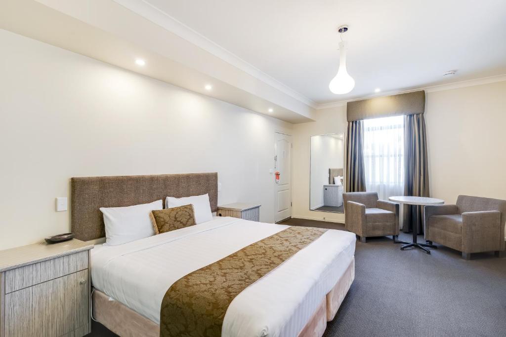een hotelkamer met een bed en een tafel en stoelen bij Prince of Wales Hotel in Wagga Wagga