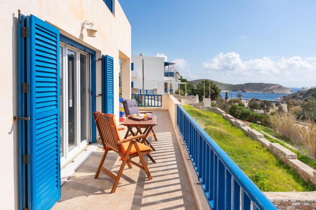 a balcony with blue shutters and a table with a laptop at Villa Zenia Syros in Vári