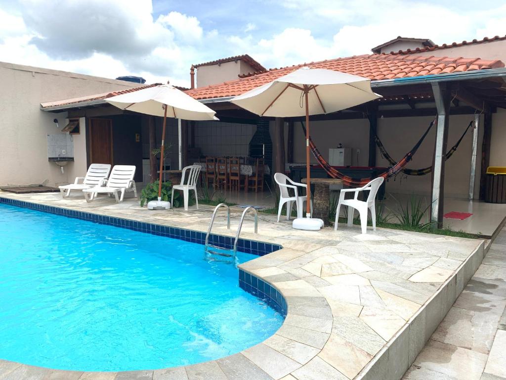 a swimming pool with chairs and umbrellas next to a house at Casa 2M no Centro de Piri in Pirenópolis