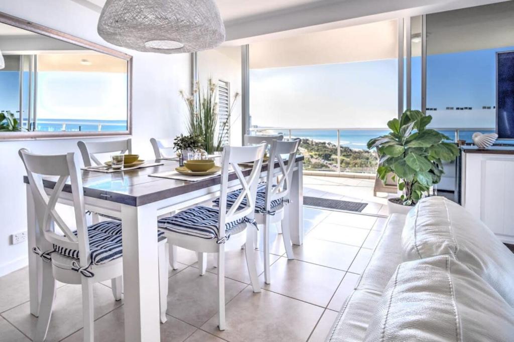 uma sala de jantar com uma mesa e cadeiras e um sofá em Panoramic Ocean Views At Maroochydore em Maroochydore