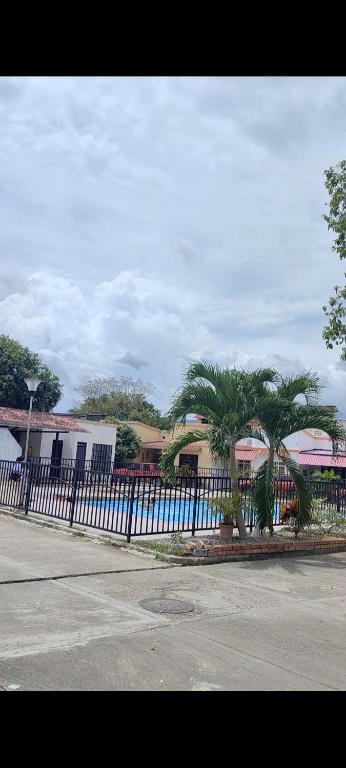 a fence with palm trees in front of a building at VILLA DEL SOL PURIFICACIÓN TOLIMA in Purificación