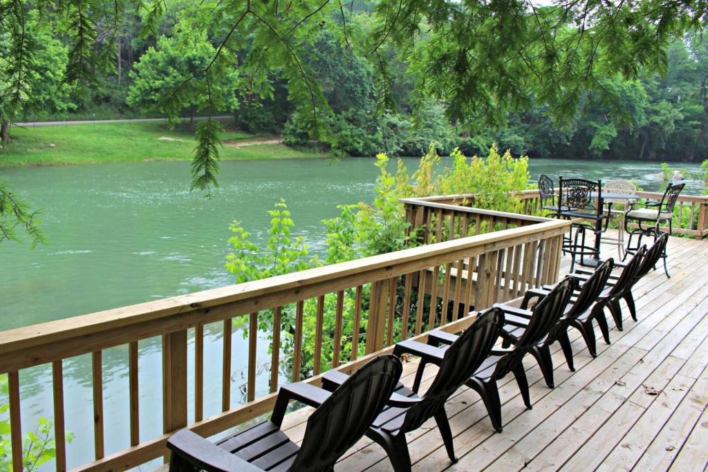a row of chairs sitting on a deck next to a river at Guadalupe River Getaway - 140 Feet of Beautiful Waterfront! in New Braunfels