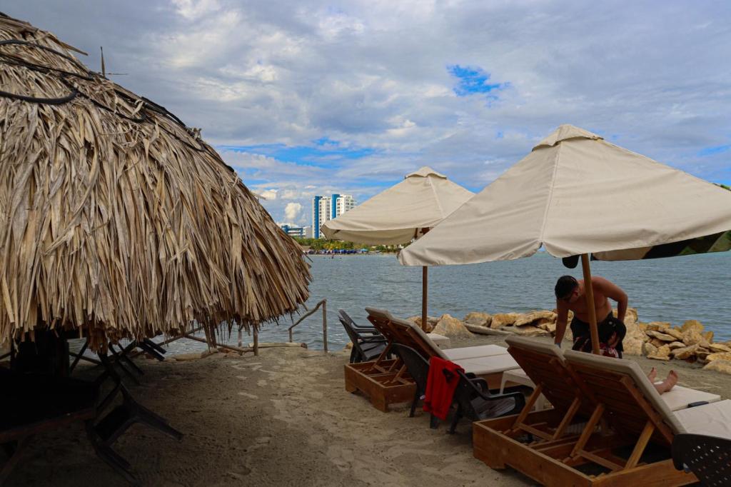 un hombre sentado en una playa bajo sombrillas en Hotel Costa Mar Coveñas en Coveñas