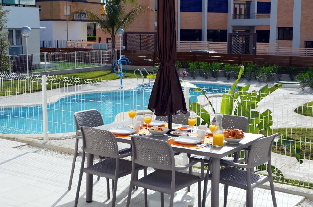 una mesa y sillas con comida junto a una piscina en El Mirador de la Ribera - 7408, en Santiago de la Ribera