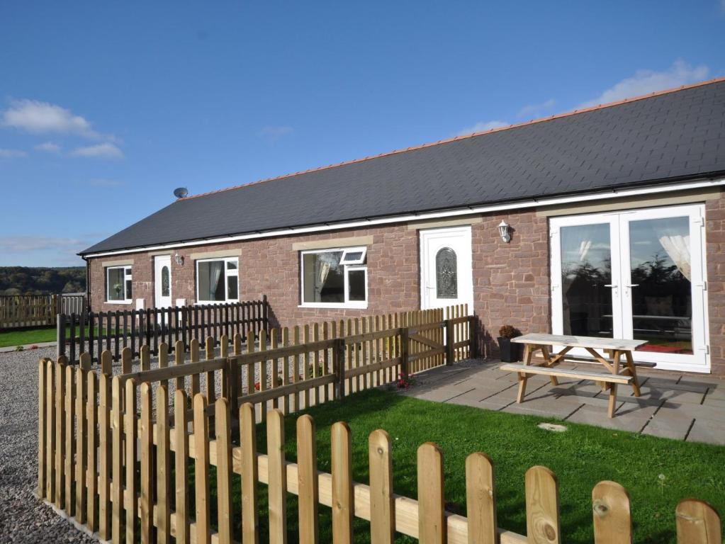 a house with a wooden fence and a wooden picnic table at 2 Bed in Blakeney 54766 in Awre