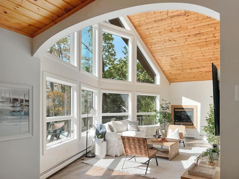 a living room with white furniture and large windows at Lakeside Oasis in Kalkaska