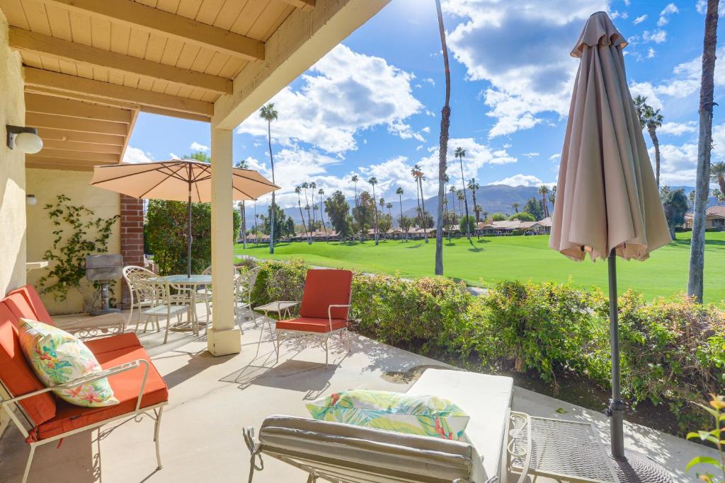 a patio with chairs and an umbrella and a golf course at Stunning Palm Desert Condo with Golf Course Views! in Palm Desert