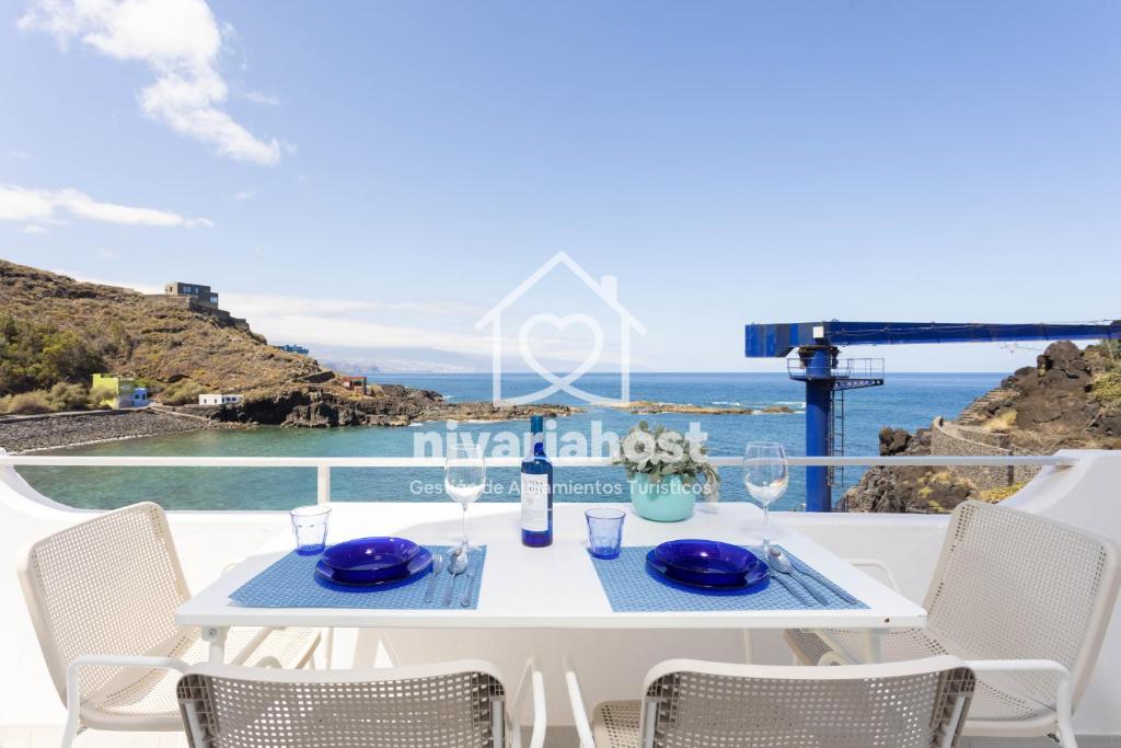 a table with blue plates and wine glasses on a balcony at Ocean View El Pris, by Nivariahost in El Pris