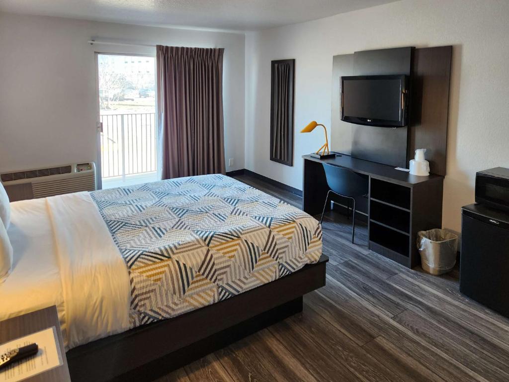 Habitación de hotel con cama, escritorio y TV. en Motel 6-Lincoln, NE - Airport, en Lincoln