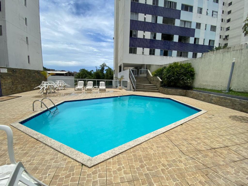 una piscina con sillas y un edificio en Aconchegante e bem localizado, en Salvador