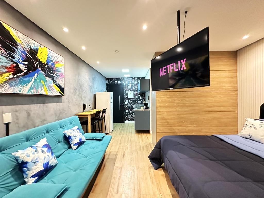 a bedroom with a blue couch and a tv at Rover Centro in Sao Paulo