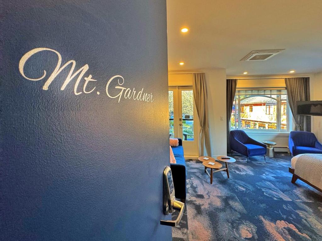 a living room with blue chairs and a sign on a wall at Artisan Suites on Bowen in Bowen Island