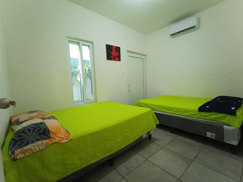 2 camas en una habitación con sábanas verdes en CASA PARLAMAR, en Monterrico