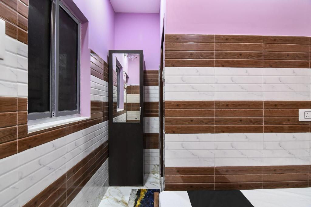 a bathroom with purple walls and a mirror at Super OYO PPS NEST Guest House in Kolkata