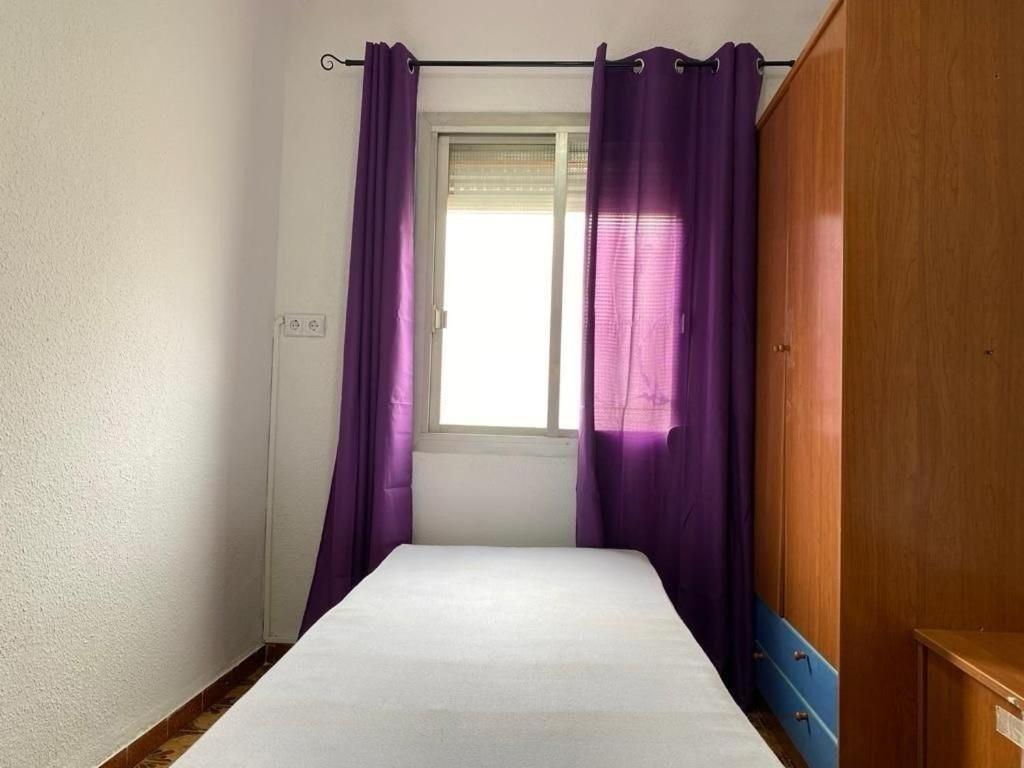 a small bedroom with purple curtains and a window at Oran in Oran