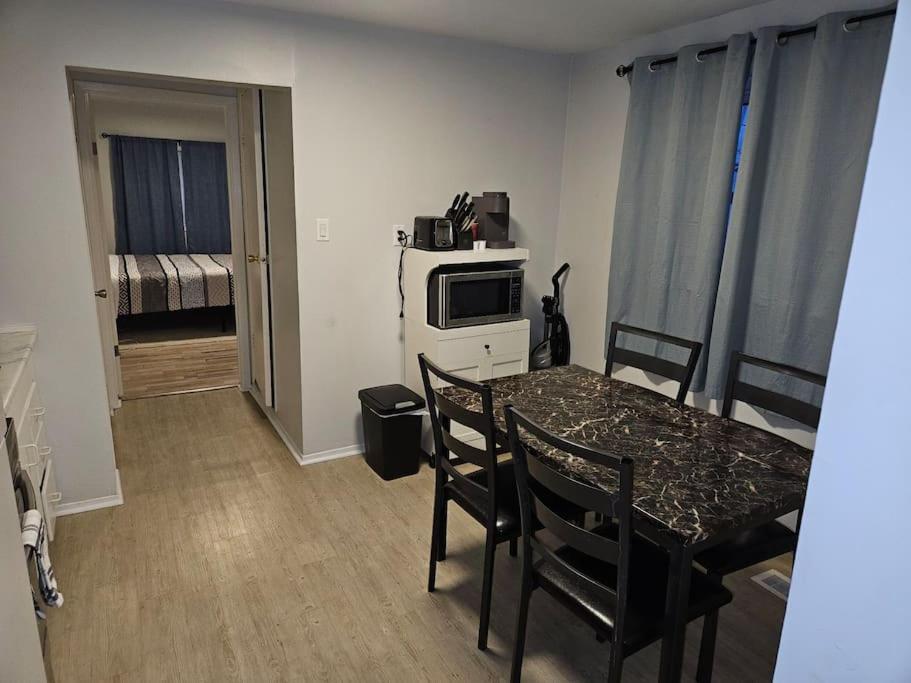 a kitchen with a table with chairs and a microwave at Cozy and quiet apartment in Sudbury