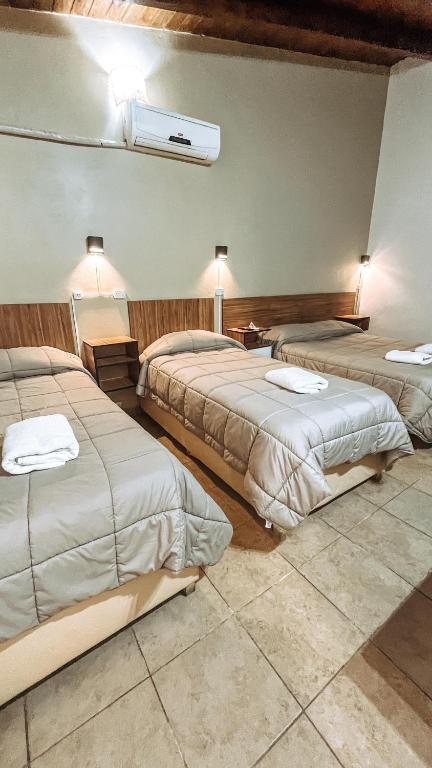 a hotel room with three beds in a room at Hospedaje Los Ilustres in Tunuyán