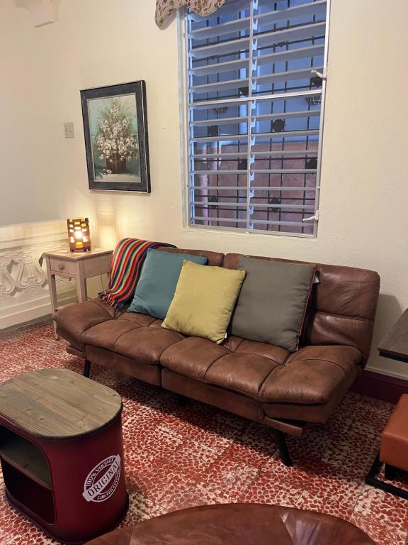 sala de estar con sofá marrón y ventana en Spa Apartment, en Mayagüez