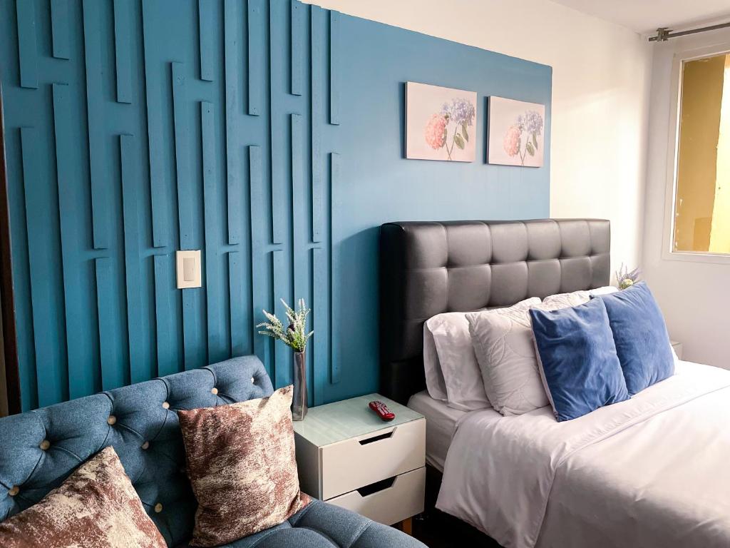 1 dormitorio con cama y pared azul en Apto tipo loft ubicado en Normandia, en Bogotá