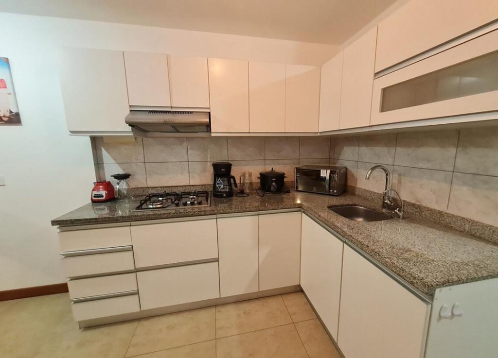 uma pequena cozinha com armários brancos e um lavatório em Apartamento exclusivo Familiar 306 em San Bartolo