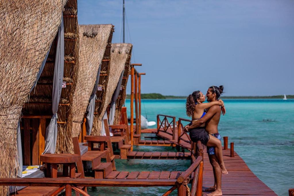 a man hugging a woman on a dock in the water at El Búho Lagoon Bacalar in Bacalar