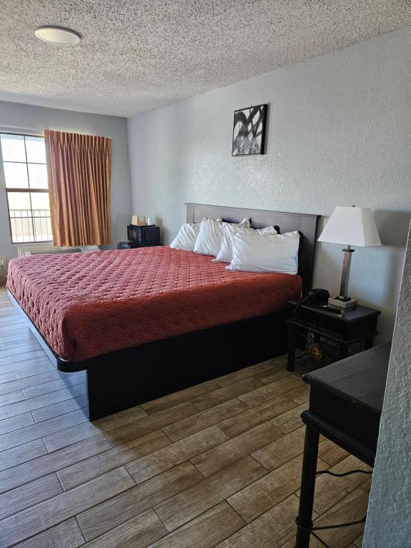 a hotel room with a bed with a red bedspread at Motel 9 in Laredo