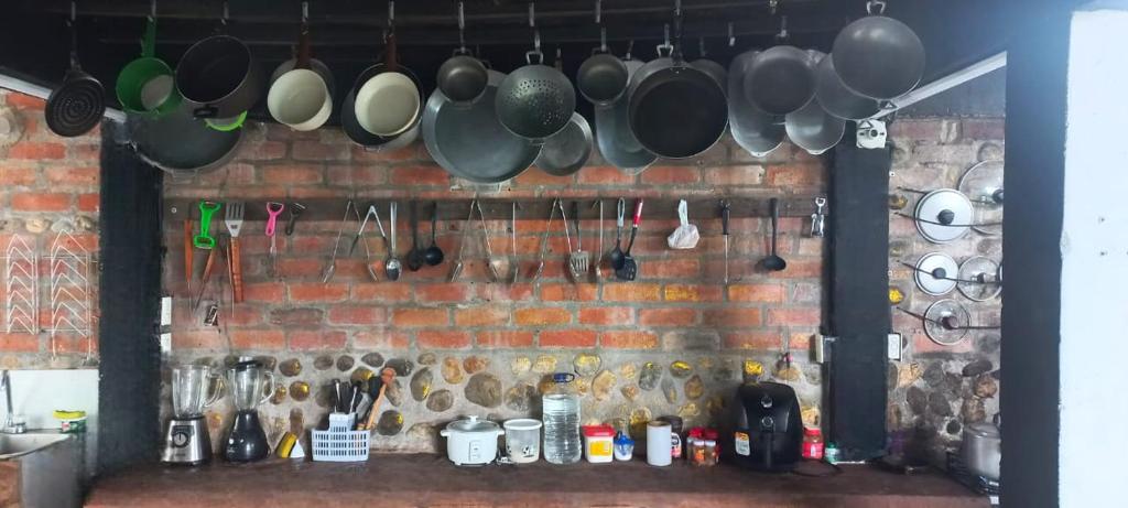 a wall with pots and pans hanging from a brick wall at Villa Tikuna in Mariquita