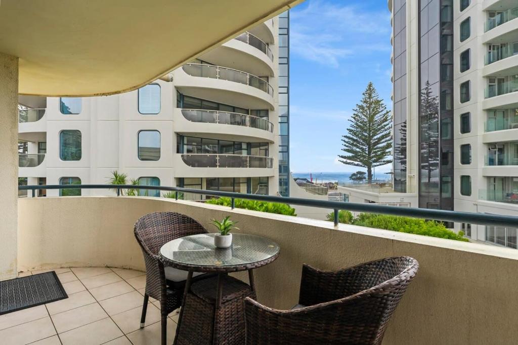 a balcony with a table and chairs and a view of the ocean at Beach Views at Oceanside in Mount Maunganui